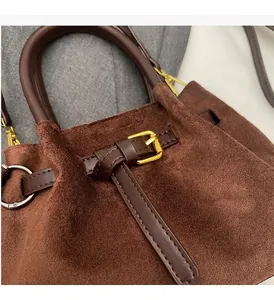 Primer plano detallado del bolso cubo de ante marrón oscuro con herrajes dorados lujo