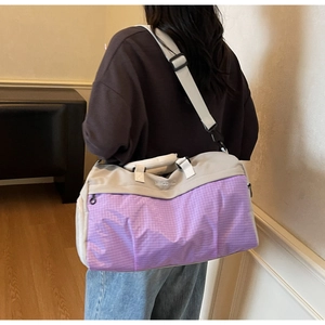 Rear view of a model carrying a large gray and purple color-block waterproof travel bag