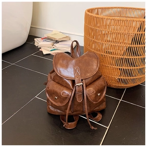 Detail of vintage brown leather backpack showing contrast stitching and metal buckle closure