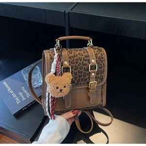 Close-up of retro leopard print flap and brown leather buckles on mini backpack