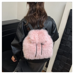 Close-up of pink faux fur backpack with decorative drawstring and black webbing straps