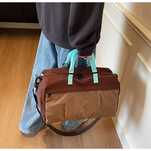 Detail of waterproof travel bag featuring mint blue straps and brown plaid patchwork design