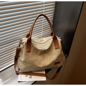Detailed close-up of beige canvas tote bag showing brown straps and leather logo patch