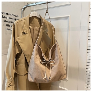Detail of soft beige suede hobo bag with drawstring bow knot and minimalist design