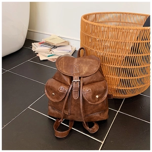 Detailed view of vintage brown leather backpack with contrast stitching and buckle pockets