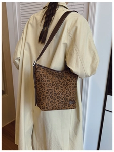 Détail du sac seau à imprimé léopard avec bandoulière en cuir brun et logo