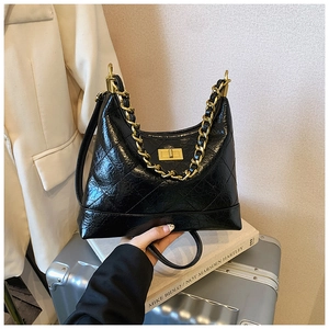 Détail du sac en cuir verni matelassé noir avec chaîne dorée et fermoir tournant
