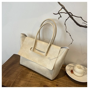 Detailed close-up of cream leather tote bag on wooden table with elegant home decor