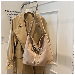 Detail of apricot suede Hobo bag with decorative bow hanging on a golden hanger
