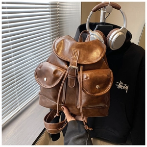 Detail of dark brown vintage backpack featuring white contrast stitching and buckle pockets