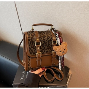 Detail of retro leopard print backpack with brown leather straps and plush bear charm decor