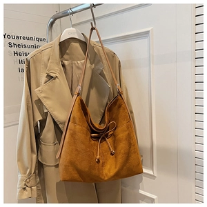 Close-up of caramel suede tote bag featuring drawstring bow and side pocket detail