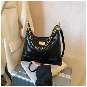 Détail d'un sac en cuir noir matelassé avec chaîne dorée et fermoir rotatif