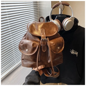 Detail of vintage brown leather backpack showing magnetic buckle pockets and texture