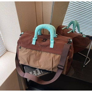 Detail of waterproof travel bag featuring brown plaid stitching and blue padded handles
