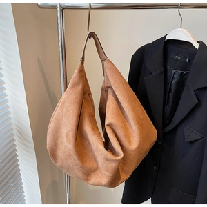 Vue détaillée du grand sac cabas en daim marron suspendu sur un support métallique chic