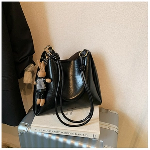 Detail of a black oil wax leather tote bag with a cute plaid rabbit plush pendant