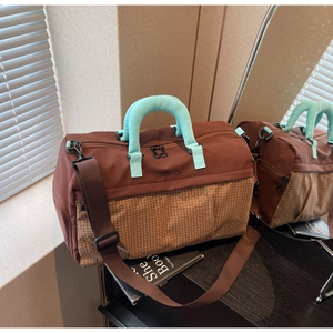 Detail view of large travel bag featuring brown and teal color-blocking with checkered texture