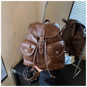 Detail view of dark brown PU leather backpack with contrast stitching and multi-pockets