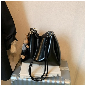 Detail of black glossy tote bag featuring knot handle design and cute rabbit charm pendant
