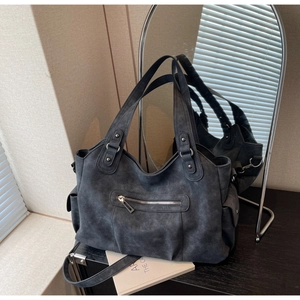 Detail showing the retro grey tote bag with metallic studs and large side pocket