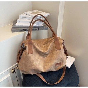 Detail view of khaki canvas tote bag with vintage texture and brand leather patch