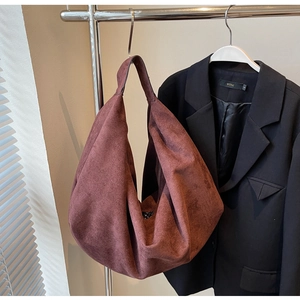 Gros plan d'un grand sac hobo en daim bordeaux suspendu avec une texture mate premium