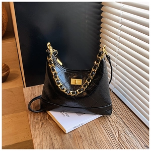 Détail du sac hobo matelassé noir avec chaîne dorée épaisse et fermoir pivotant chic