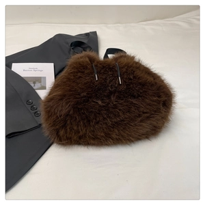 Macro detail of plush coffee brown faux fur bucket bag with black drawstring and metal tips