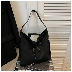 Detail of minimalist black hobo bag with frosted texture and elegant bow drawstring