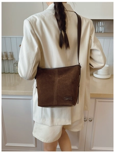 Détail du sac seau en daim marron foncé montrant la texture et l'étiquette de marque