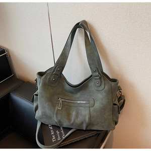 Detail of dark green vintage tote bag with metal zipper and matte leather texture