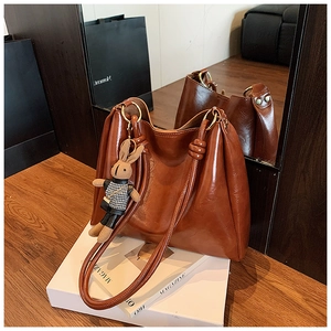 Close-up of brown oiled leather tote bag with round gold hardware and cute bunny charm