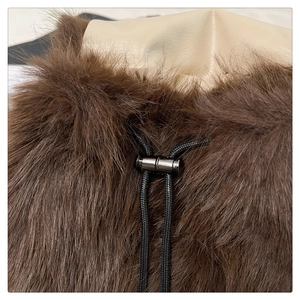 Detail view of brown plush material with a black woven drawstring and metal cord lock