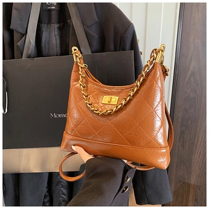 Gros plan du sac hobo matelassé marron caramel avec chaîne dorée et fermoir rotatif