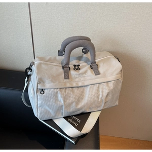 Close-up of large travel bag with dual zippers and embroidery on a leather sofa