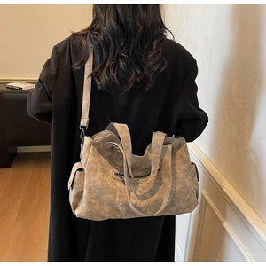 Model wearing a large vintage leather tote bag with side pockets and a long strap