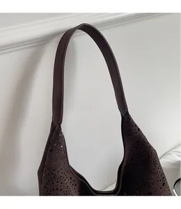 Close-up of laser-cut hollow pattern on dark brown faux leather hobo shoulder bag
