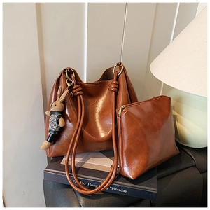 Detailed view of brown leather tote bag set with a cute bunny charm on a dark desk