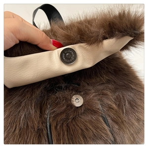 Detail of magnetic buckle closure on a brown faux fur backpack with beige leather lining
