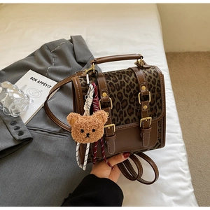 Detail view of leopard print backpack with brown leather straps and cute plush bear charm