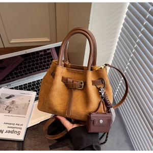 Detailed view of brown suede bucket bag with leather straps and decorative scarf accessories