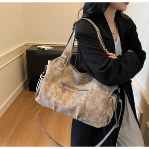 Detailed view of a vintage taupe tote bag with side button pockets and metal zippers