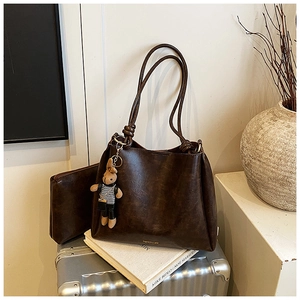 Detail of dark brown vintage oil wax leather tote bag with a small pouch and rabbit charm