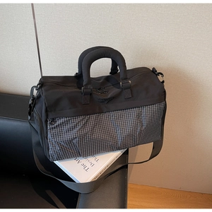 Detail showing high-capacity black nylon travel bag with grid pattern and padded handle