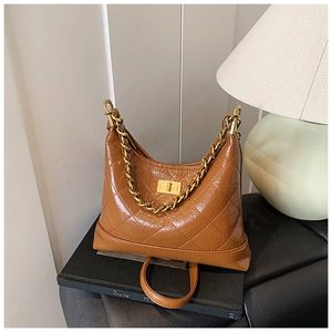Détail d'un sac à main marron en cuir matelassé avec chaîne dorée et fermoir pivotant carré