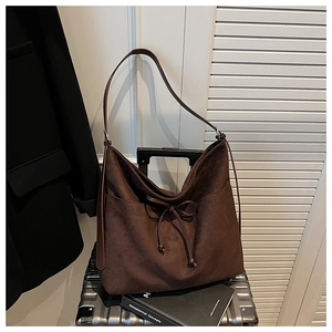 Detail of dark brown faux suede hobo bag with drawstring on silver metallic suitcase