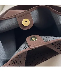 Close-up of golden magnetic closure and hollowed-out pattern on brown tote bag