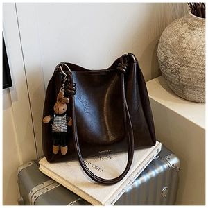 Detail of dark brown faux leather bucket bag with fashion lettering and cute bunny charm