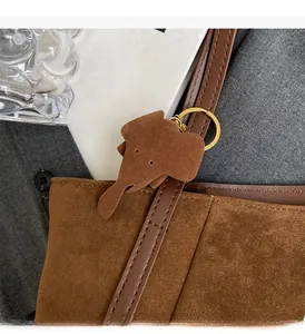 Detail of suede tote bag featuring a leather elephant charm and gold metal hardware